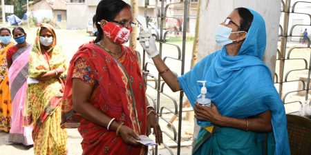 A volunteer conducting thermal screening of the voters, at a polling booth, during the third phase of the West Bengal Assembly Election, in Uluberia, West Bengal