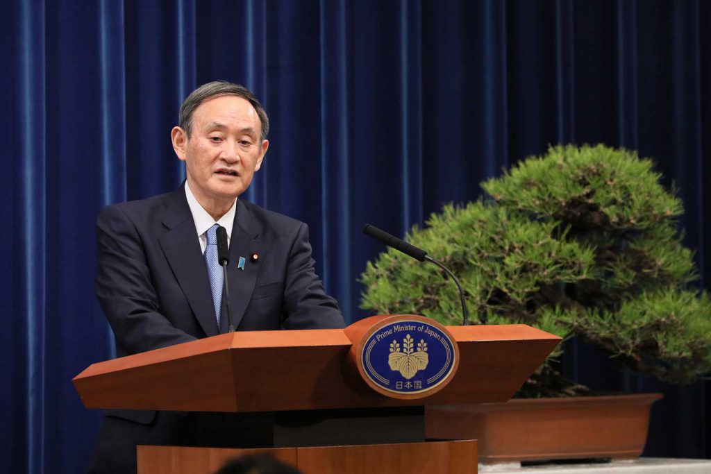 Japanese Prime Minister Yoshihide Suga standing at a podium