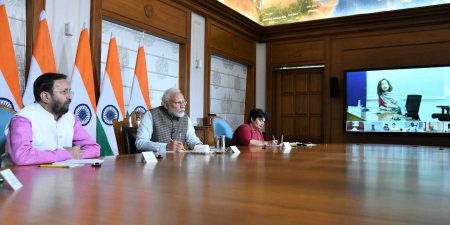 Prime Minister Modi sitting at a board room table speaking to journalists