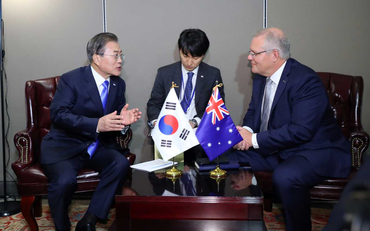 Moon Jae-in and Scott Morrison sitting at a table with the South Korean and Australian flags