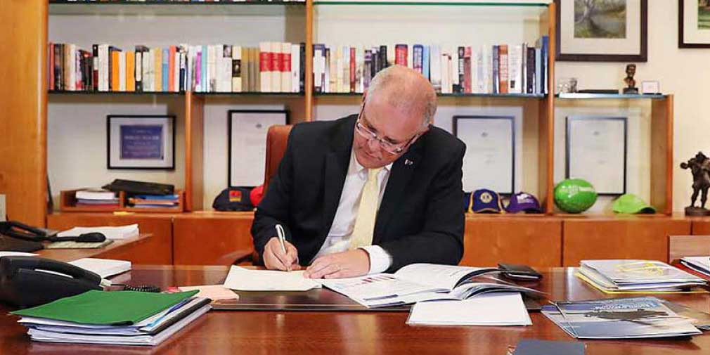 Prime Minister Scott Morrison signing papers at his desk