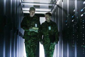 Two uniformed military men walking down a dark corridor