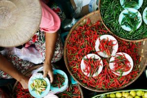 Overhead shot of person sitting with many large bowls of chili peppers