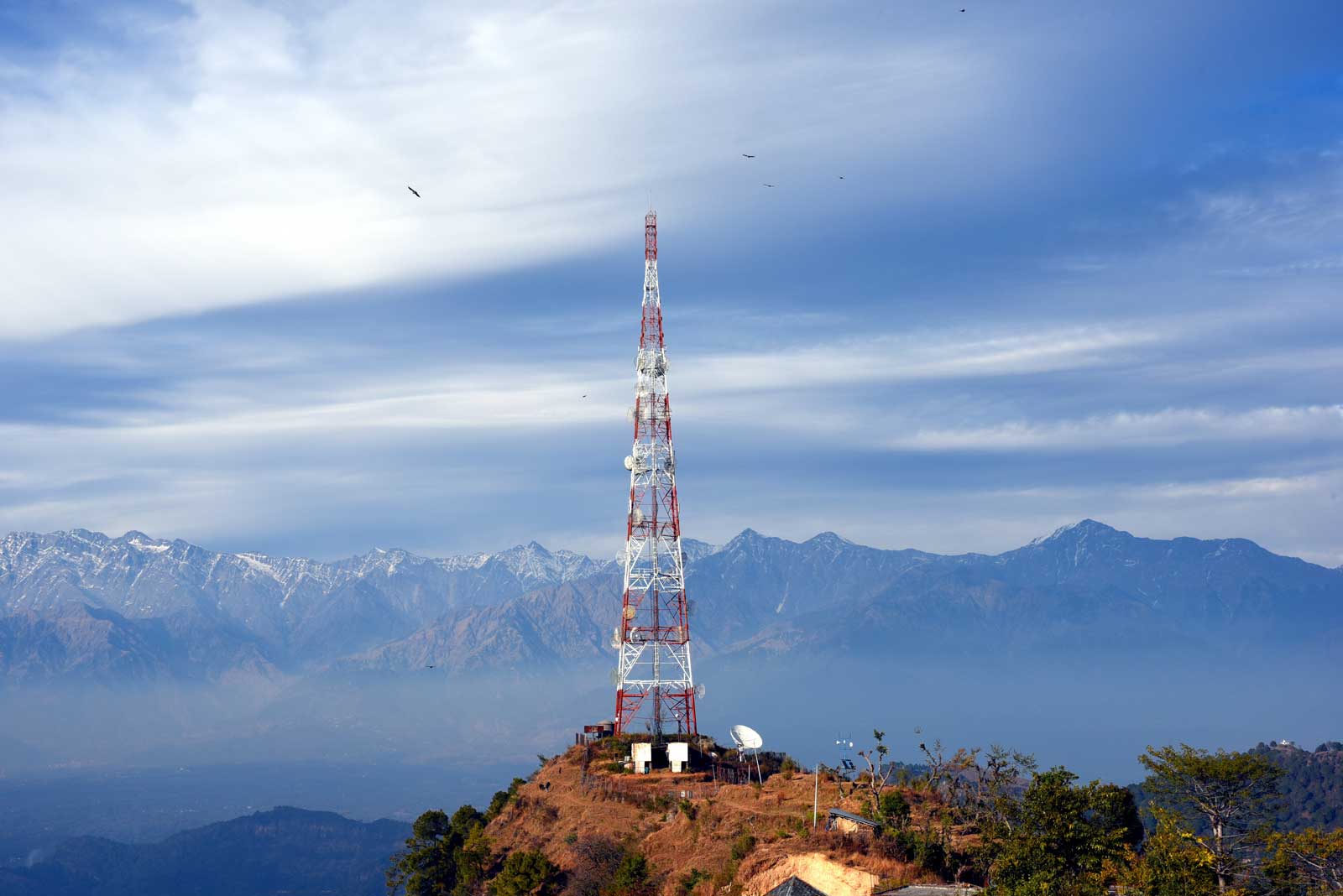 A radio tower surrounding by beautiful mountains