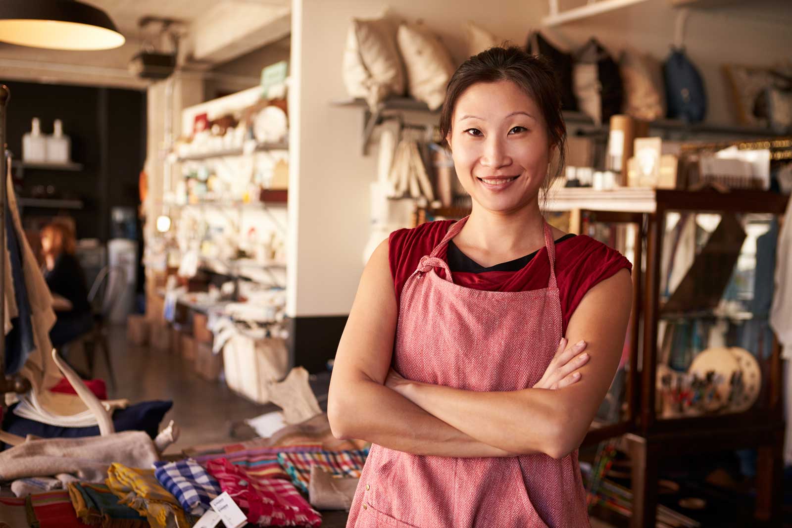 A smiling woman with arms crossed standing in a textile shop