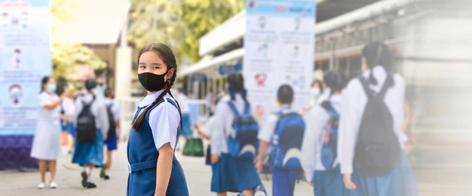 A young child in school uniform wearing a face mask